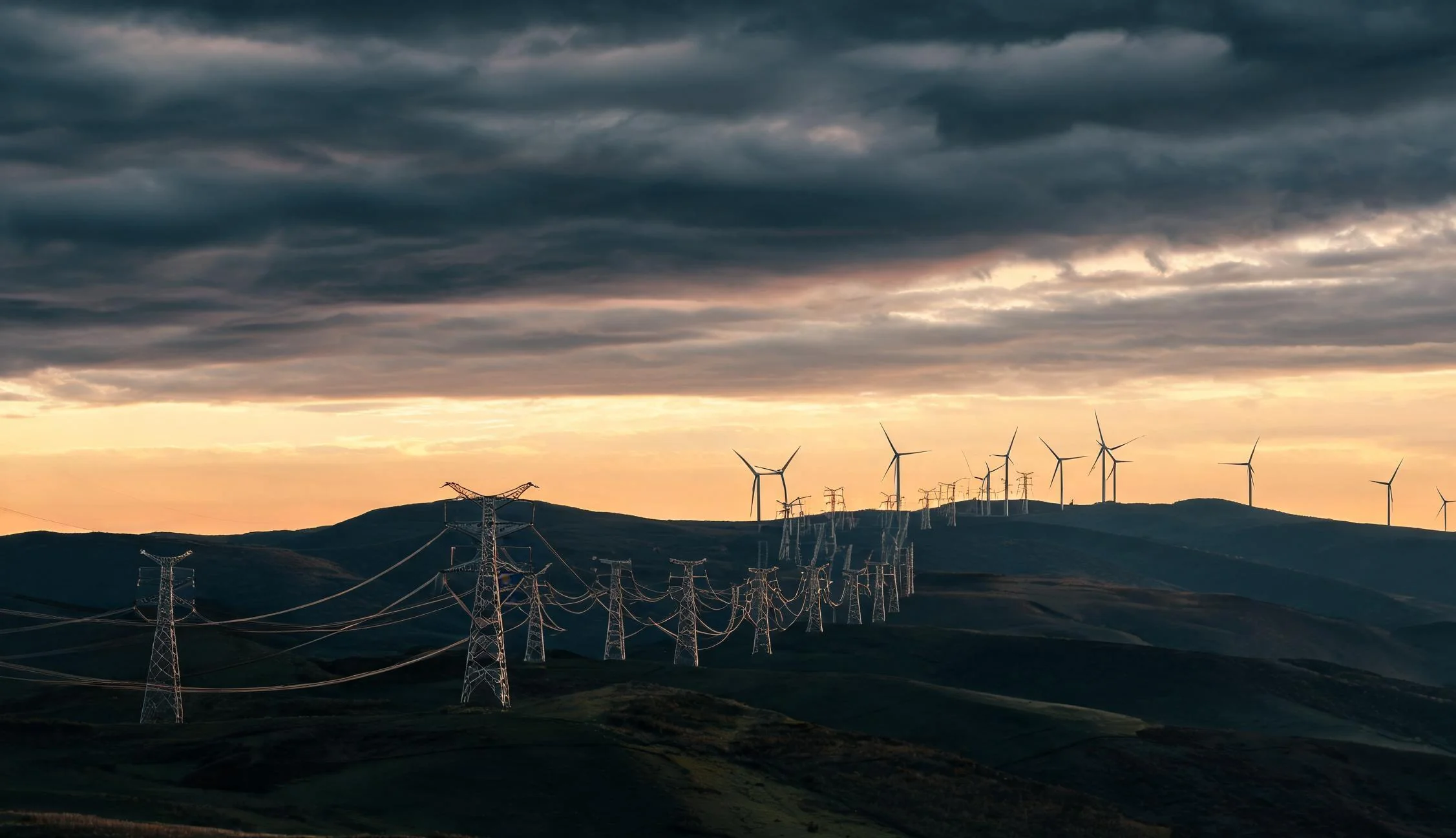 Thema II Energiewende und Netze: Hochspannungsmasten und Windkraftanlagen in der Abenddämmerung